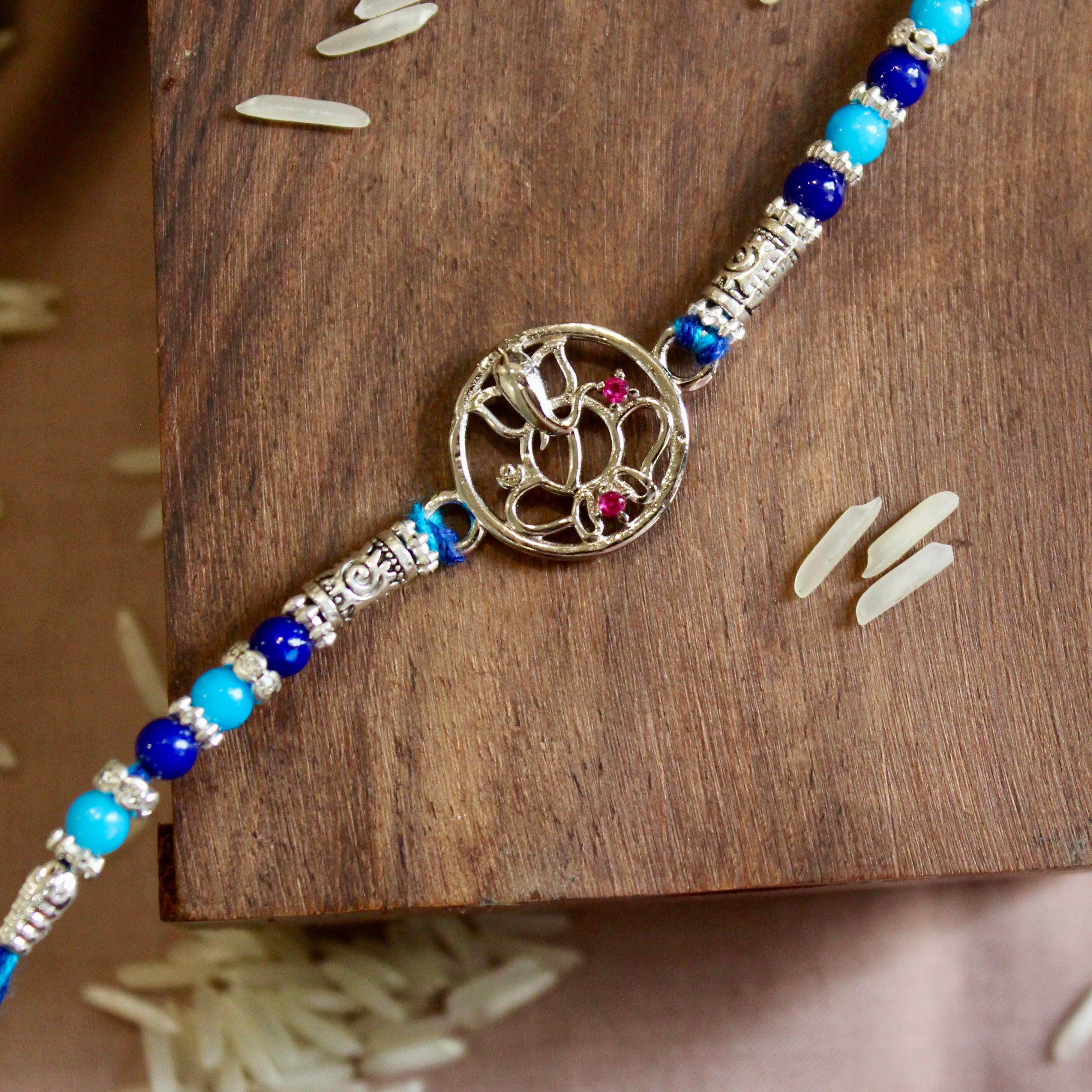 Lord ganesha with stones blue thread rakhi in 925 silver