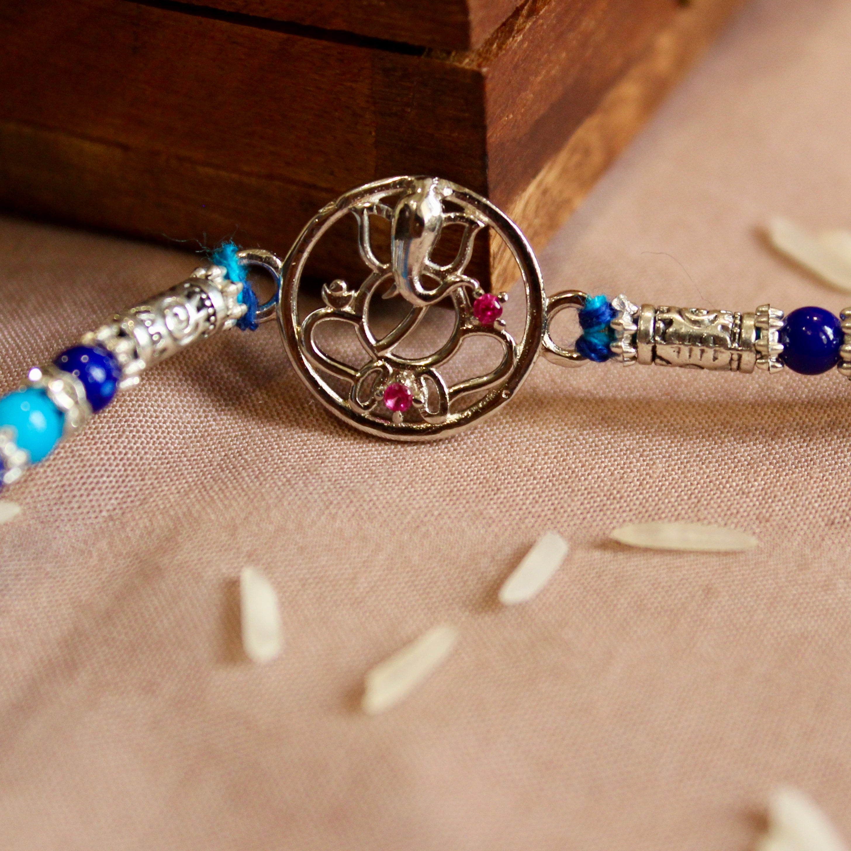 Lord ganesha with stones blue thread rakhi in 925 silver