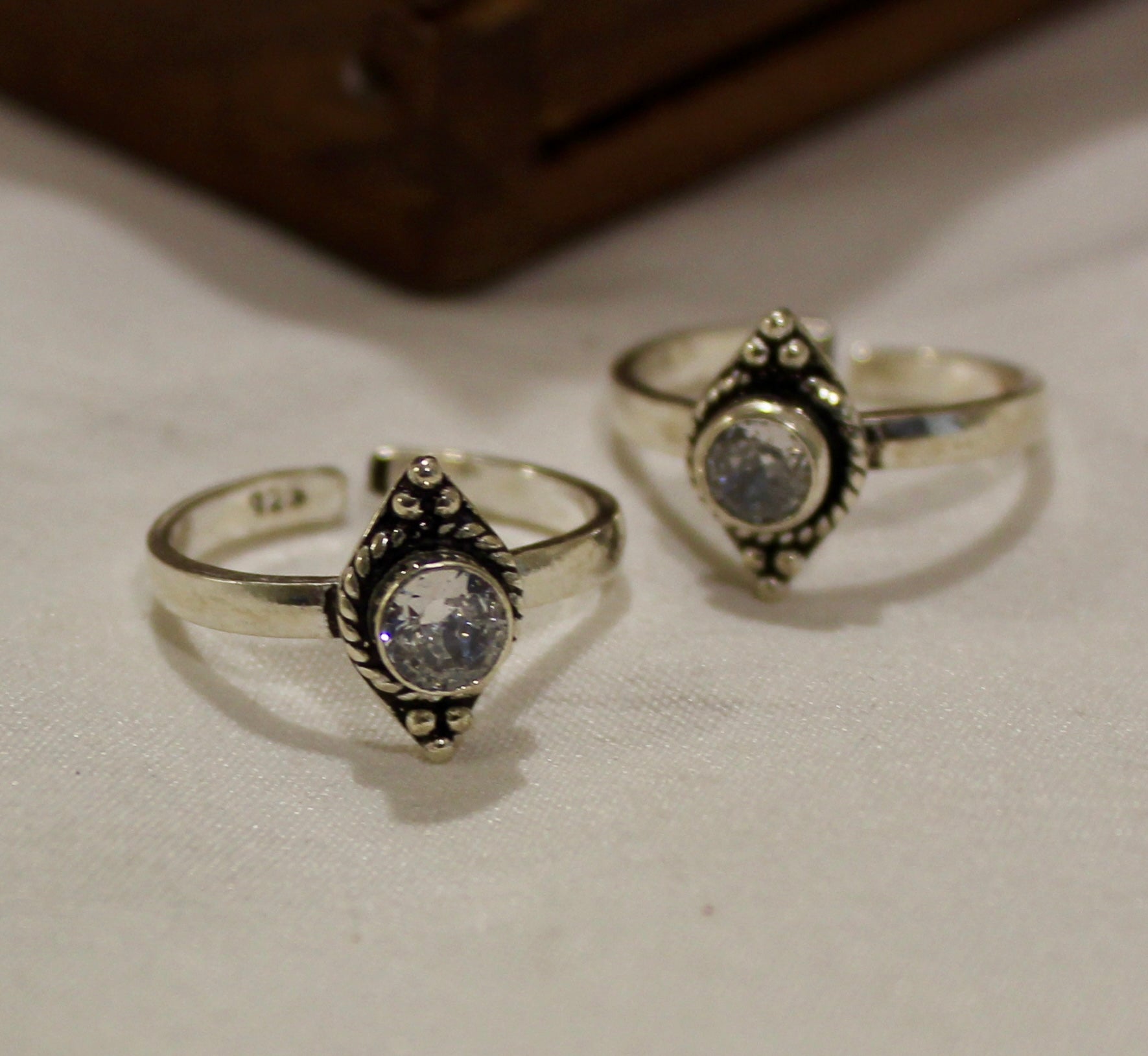 Close-up of a foot wearing two silver rings with a gold and green traditional garment.