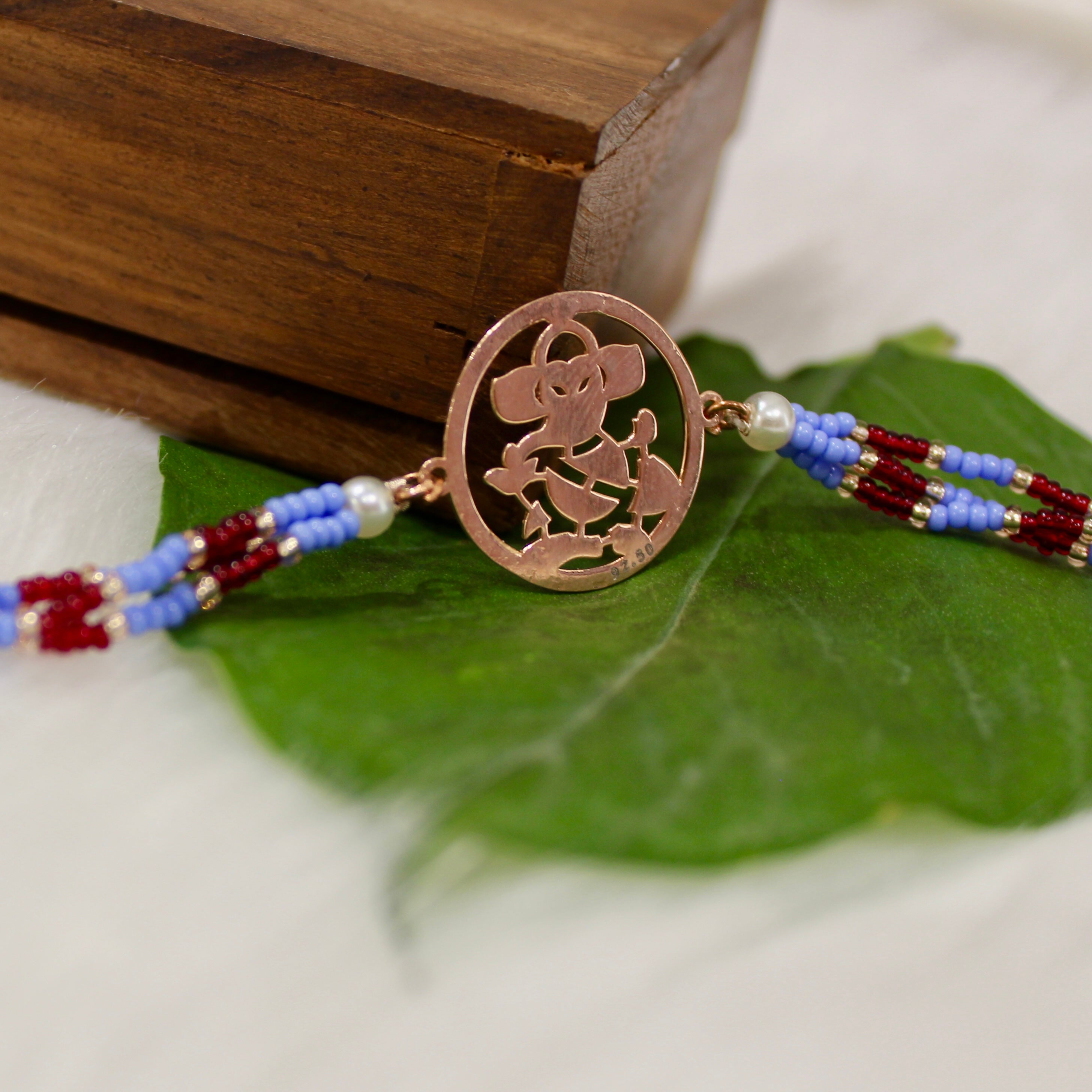 Ganesh Ji In Rosegold Polish With Purple Thread Rakhi In 925 Silver
