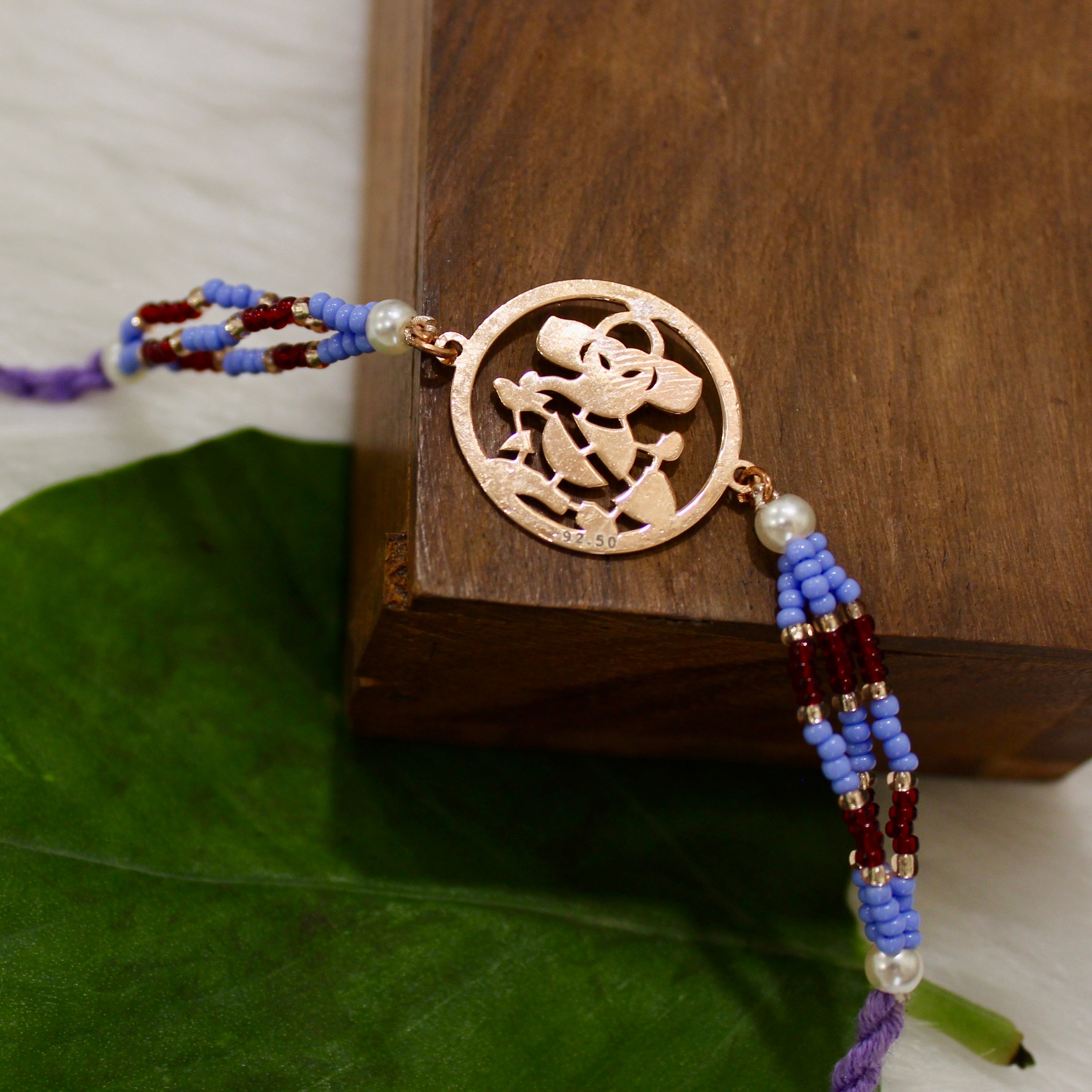 Ganesh Ji In Rosegold Polish With Purple Thread Rakhi In 925 Silver