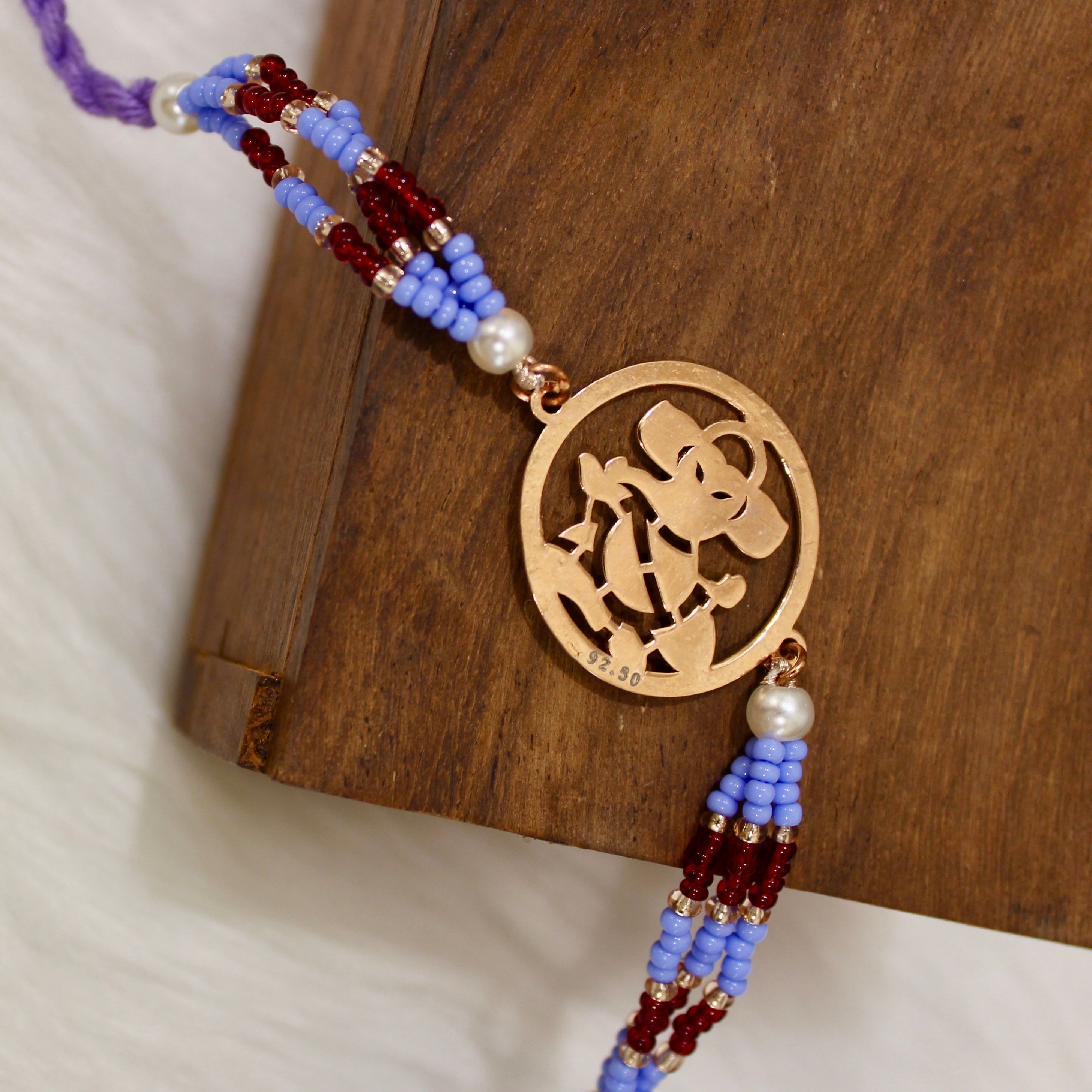 Ganesh Ji In Rosegold Polish With Purple Thread Rakhi In 925 Silver