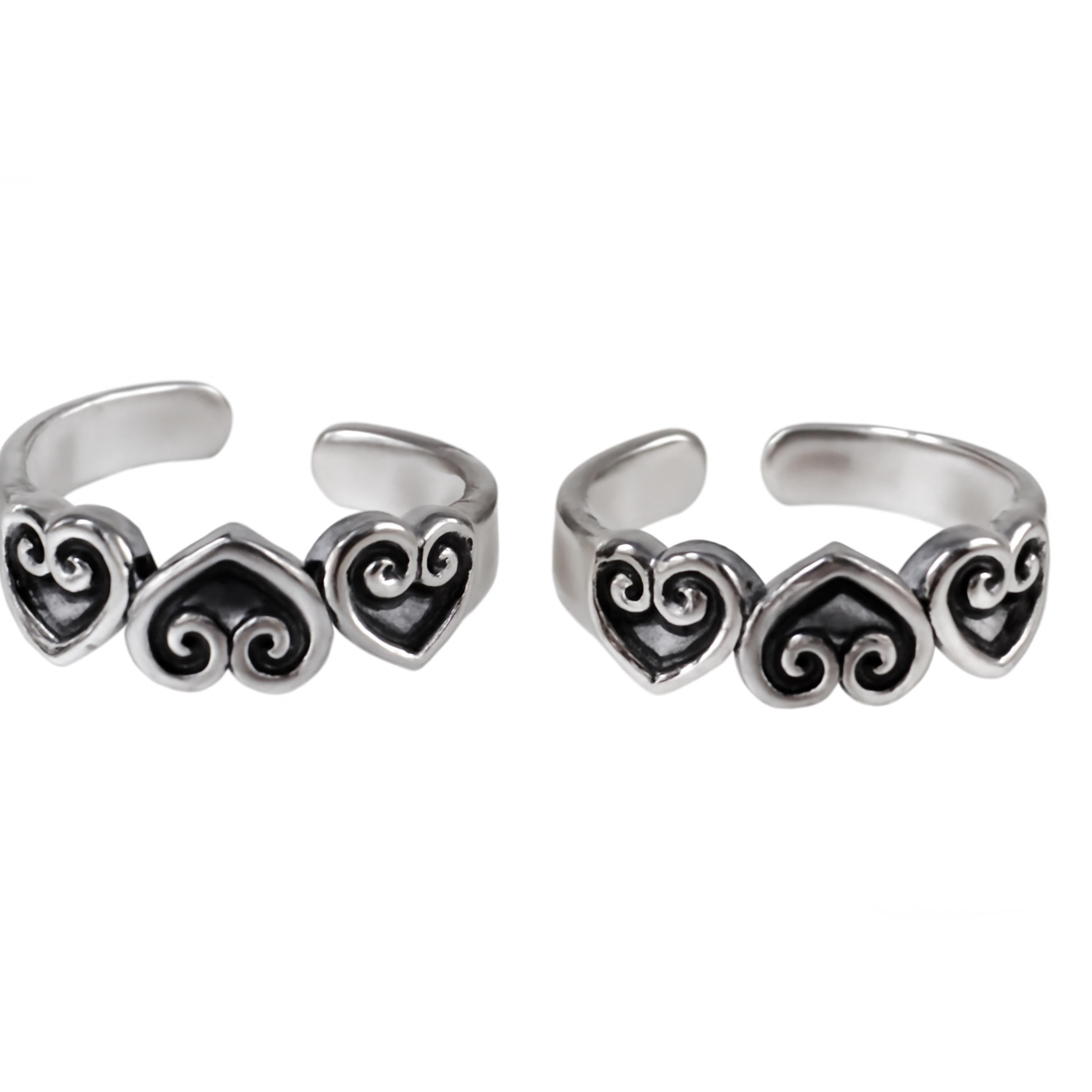 Pair of silver toe rings with heart and swirl designs on a white background