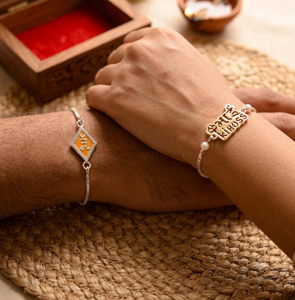 Two silver bracelets worn on crossed forearms, one with a diamond-shaped orange and gold emblem and the other with a 'Happy Class' nameplate, set on a woven mat with warm decorative background elements.