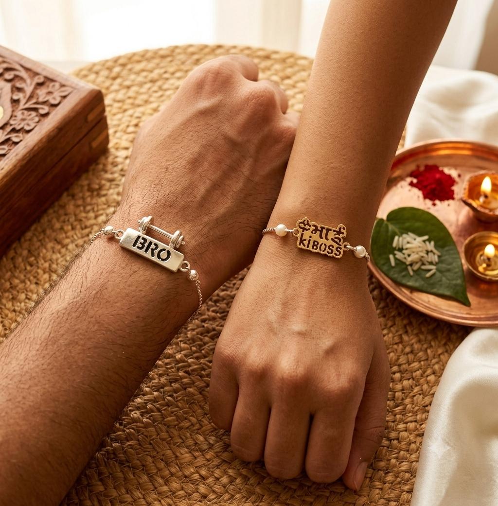 Two silver-toned friendship bracelets worn on wrists, one engraved with 'BRO' and the other with 'KIBOSS', displayed on hands over a woven mat with decorative props.